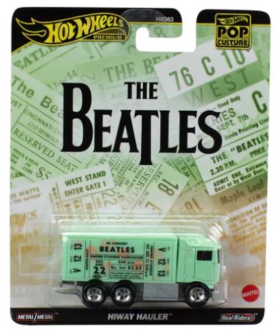 The product image shows a Hot Wheels toy car model representing The Beatles' Highway Haulier truck, packaged in a blister pack with green, yellow, and white branding elements and a stylized backdrop. The toy is predominantly green with text and branding on the packaging.